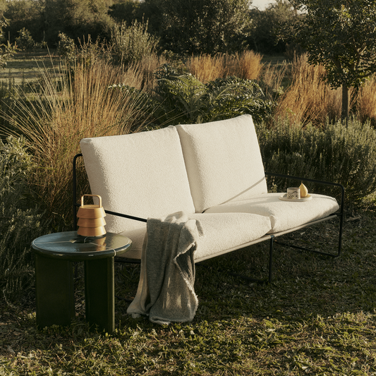 En deilig utesofa til hagen eller terrassen. Sommeren nytes aller best i tilbakelent stilling, i hyggelige omgivelser. Skap en stor, gjestfri og innbydende lounge-sone med Desert-sofa og stoler. Avbildet er 2-seter utesofa Desert i Pure Bouclé / off-white bouclé med svart understell fra Ferm Living.
