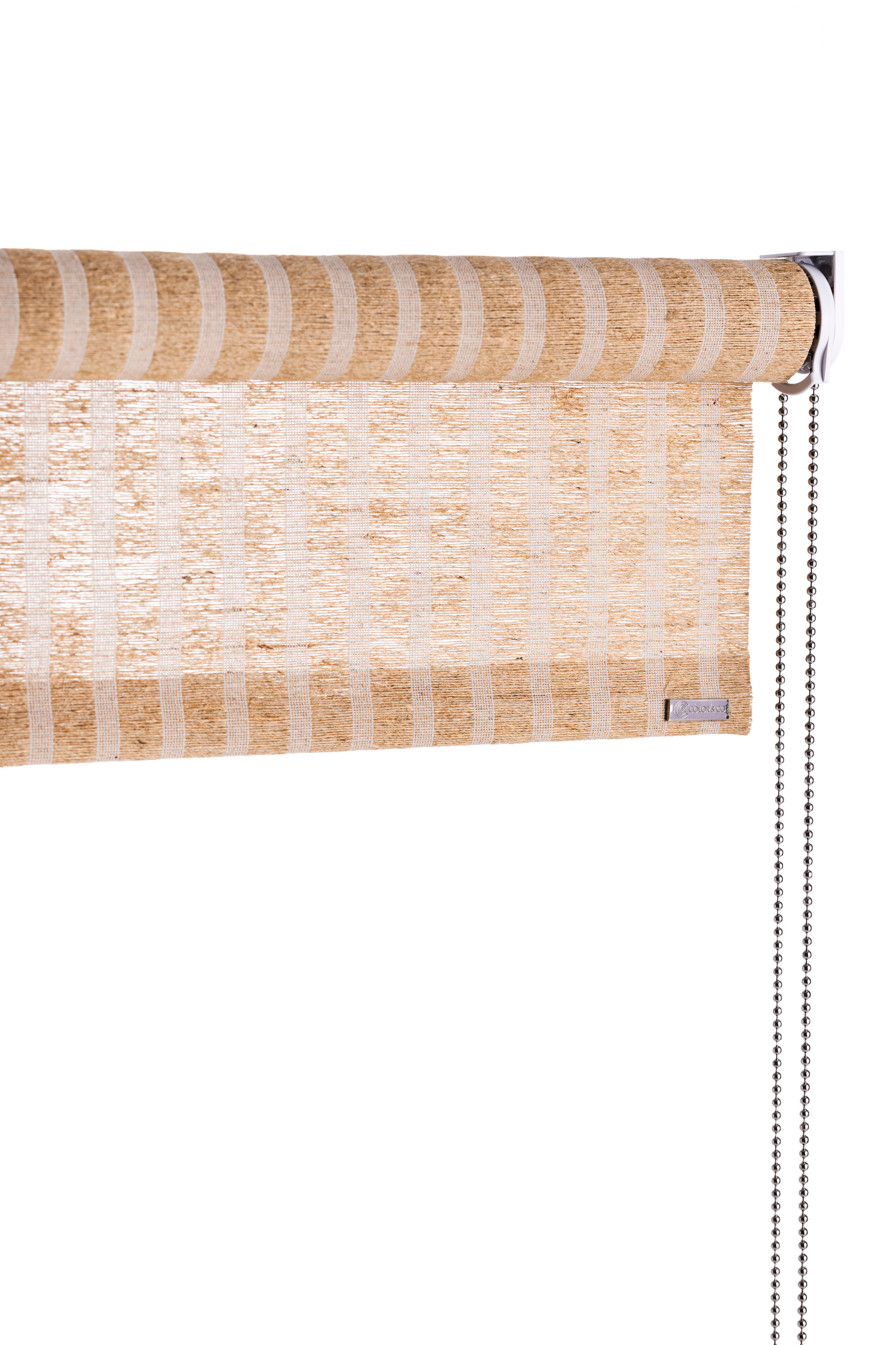 Rullegardin i brun stripet natur plante fra Color&Co med kjedetrekk: Her er fint jutegarn vevd sammen med hvit tråd i stripet mønster. Jute er et naturmateriale med en nydelig tekstur som tilfører varme i hjemmet. Denne rullegardinen fra Color&Co er finvevd i brun jute med lyse striper som er ca 1 cm brede. Gardinen er utrolig vakker, lett og eksklusiv og kan henges opp i alle rom. Gardinen har ca. 50% lysinnslipp, og gjør seg perfekt når du bare ønsker å dempe lyset, men ikke stoppe det.