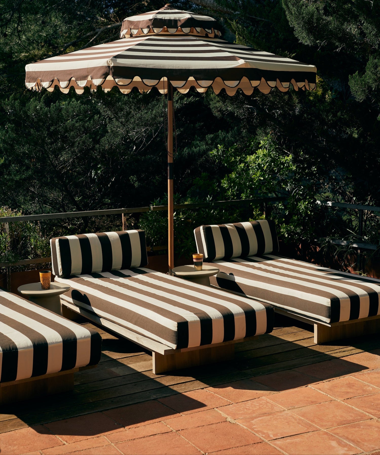 Det mørkebrune- og hvitstripete tekstilet Stracciatella, minner eksempelvis om poolside-møblene i fotografiene til Slim Aarons fra 70-tallet. Så fint! Det finnes også en matchende parasoll. samt at utesofaen i samme serie kan kles i samme tekstil som dagsengen.