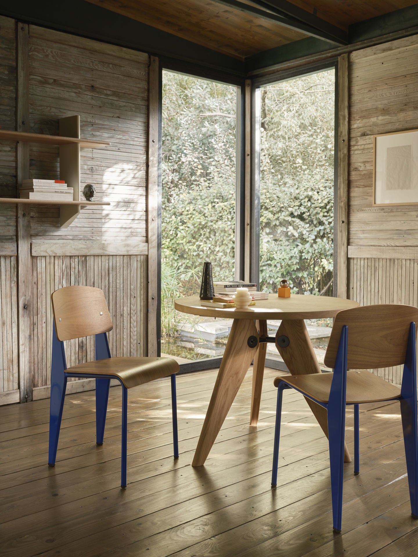 Bilde av hyllen Rayonnage Mural sammen med spisestolen Standard Chair fra Vitra, begge designet av Jean Prouvé, i originale Prouvé-farger.