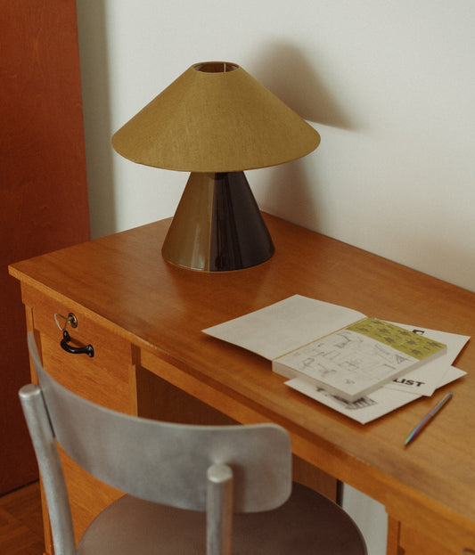 Bordlampen Caterina Golden Olive har en håndmalt tofarget lampefot i mørkebrun og gyllen olivengrønn glasert keramikk og skjerm i gyllen olivengrønn lin som sprer et behagelig og stemningsfullt varmt lys. En elegant bordlampe i en helt unik kombinasjon av farger og teksturer! Caterina står nydelig plassert på en skjenk i stue eller spisestue, på et skrivebord eller nattbord.