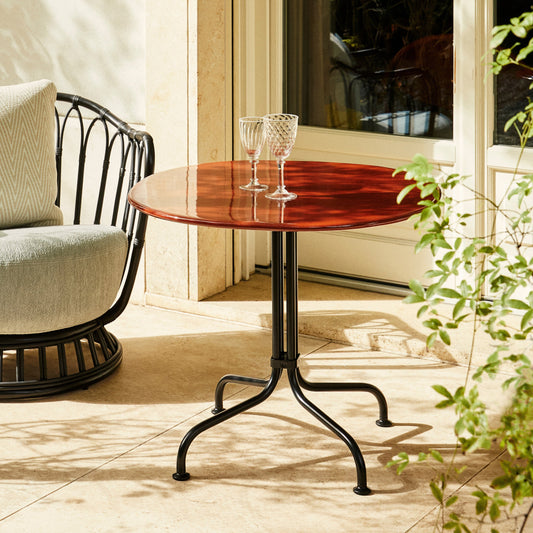 Kafébordet Carmel Bistro Lounge Table i rød/Rock Red og lenestolen Grace Outdoor Lounge Chair fra Gubi i sort/Black.