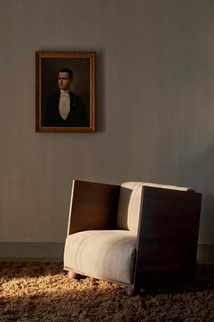 Bilde av lenestolen Rum Lounge Chair fra Ferm Living i stue. Stolen har ramme i mørkbeiset furu og myke sitteputer i lys lin.