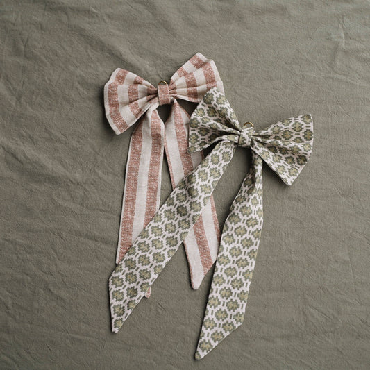 Årets julesløyfer kommer i to ulike tekstiler vi liker ekstra godt – Sverresborg og Halsa. Sverresborg-sløyfen er rødstripete og mønsteret i tekstilet er inspirert av det norske veggteppet Tavlebragd, som er en av nasjonalskattene som vises frem på Sverresborg – Trøndelags Folkemuseum. Mønsteret på det grønne tekstilet til Halsa-sløyfen er en moderne tolkning av et 500 år gammelt Åkle-veggteppemønster fra nordvestkysten. Uansett hvilken du velger får du et lite stykke norsk kulturarv inn i hjemmet.