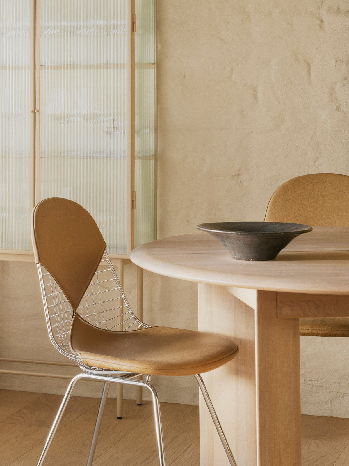 Bilde av spisestue i 60-tallsstil: Spisestolen Wire Chair DKR er designet av Charles og Ray Eames for Vitra. Dette er en skulpturell stol med polstret sete og rygg i eksklusivt skinn. Superfin i kombinasjon med et spisebord i tre!