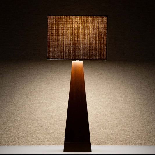 Takket være den beige tekstilskjermen avgir lampen et deilig, mykt og dempet lys som spiller på lag med og fremhever det mørke treverket.