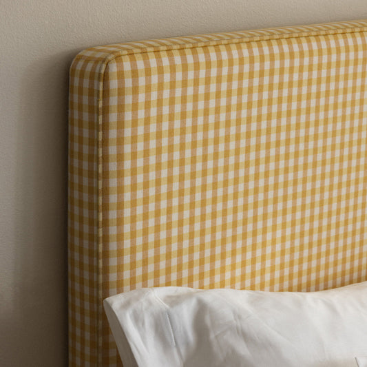 Sengegavlen Alexandra Laura er trukket i et pent gult rutemønstret tekstil og kommer i ulike størrelser.