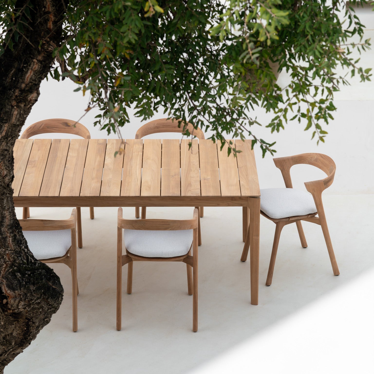Spisebordet Bok Outdoor Dining Table og spisestoler Bok Outdoor Dining Chair med puter i off white fra Ethnicraft.