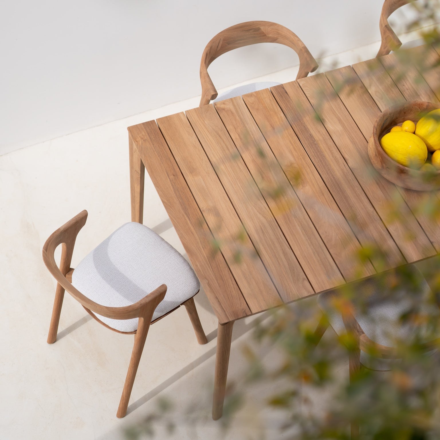 Spisebordet Bok Outdoor Dining Table og spisestoler Bok Outdoor Dining Chair med puter i off white fra Ethnicraft.