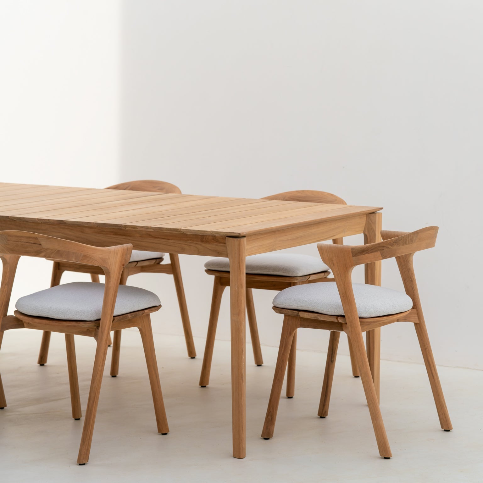 Spisebordet Bok Outdoor Dining Table og spisestoler Bok Outdoor Dining Chair med puter i off white fra Ethnicraft.