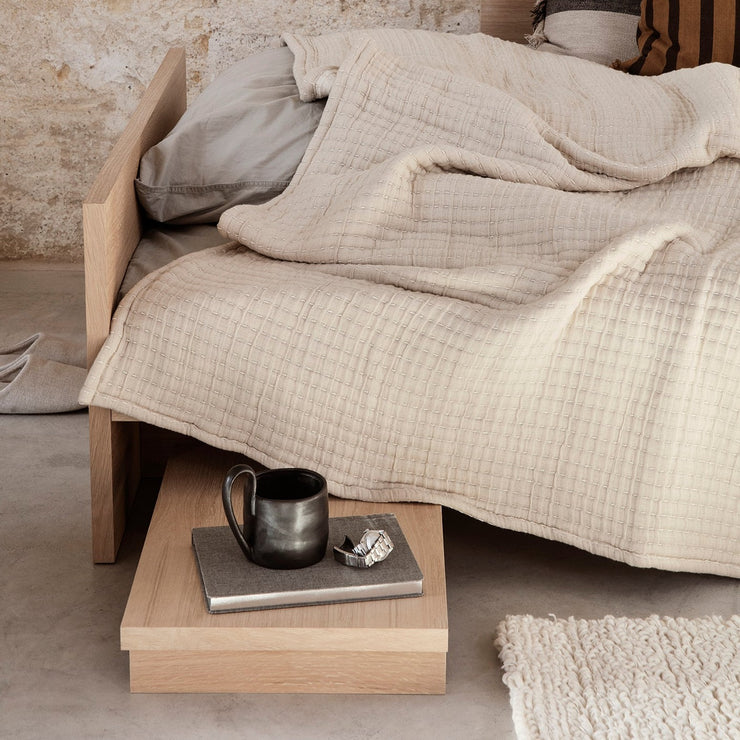Du kan la den titte frem under sengerammen for å gi en praktisk plattform for en bok, lampe og et glass vann, eller til å vise frem lekre gjenstander i stuen eller badet. På bilde er Ferm Living sitt Kona Sidebord i naturlig tre.