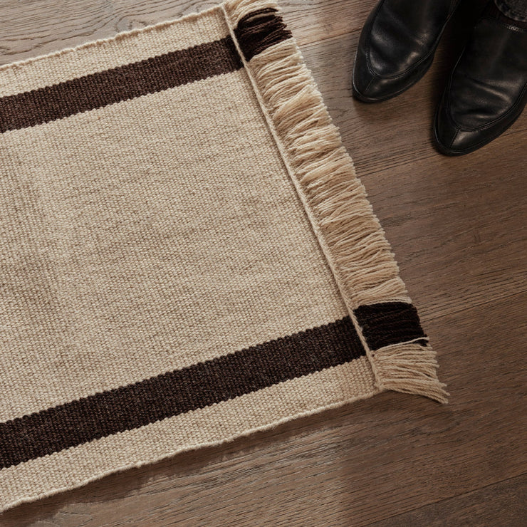 Dørmatte Calm Kelim Mat fra Ferm Living kombinerer tradisjonelt håndverk med moderne farger og mønstre. Dørmatten i fargen Coffee/Off-White