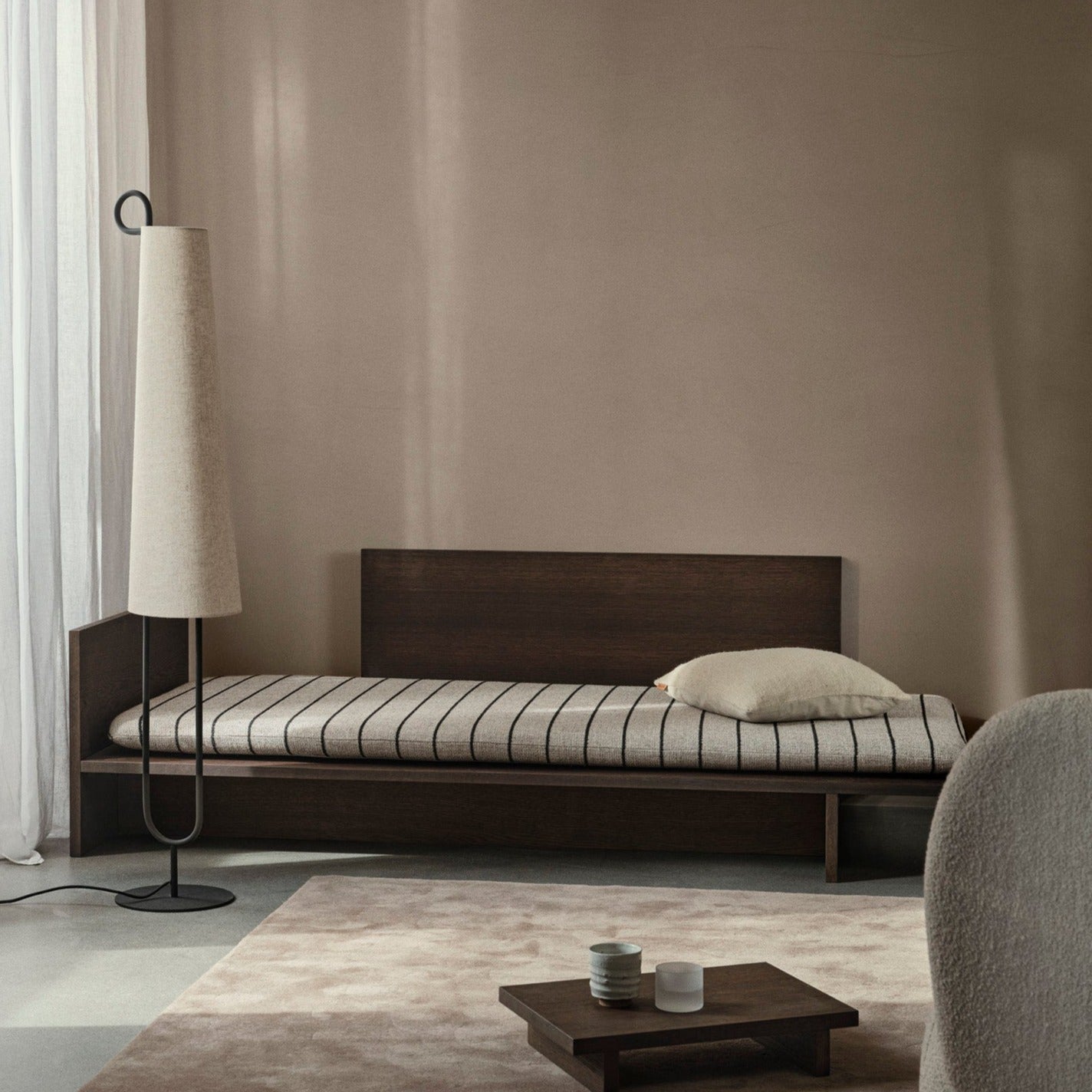 Dagseng Kona Bed i eikefiner, fra Ferm Living, i mørkbeiset utgave med madrass i det stripete tekstilet Pasadena.