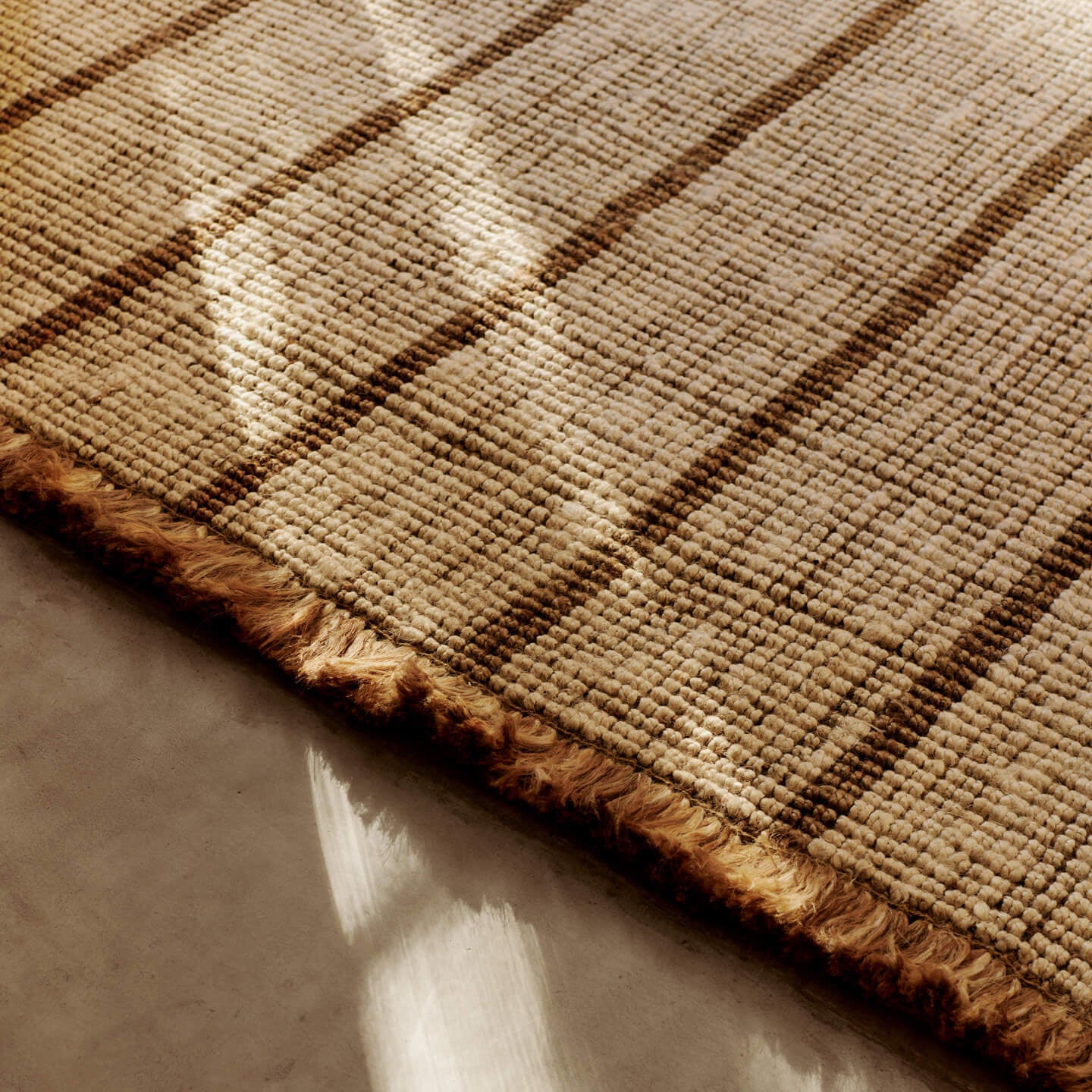 Teppe Athens Stripes Rug fra Ferm Living har tykke, myke frynser som understreker teppets mykhet og avslappede uttrykk.