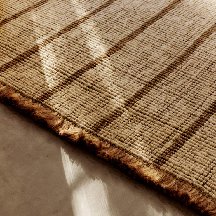 Teppe Athens Stripes Rug fra Ferm Living har tykke, myke frynser som understreker teppets mykhet og avslappede uttrykk.