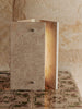 Det stramme designet til bordlampen Oeste Table Lamp fra Ferm Living står i fin kontrast til travertinens naturlige, uregelmessige tekstur, og den varme, sandfargede kalksteinen lar seg lett kombinere med andre materialer og farger i interiøret.