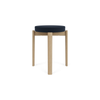 Krakk Passage Stool i eik fra Audo Copenhagen med polstret sete i tekstilet Vidar 0786 (PG3).
