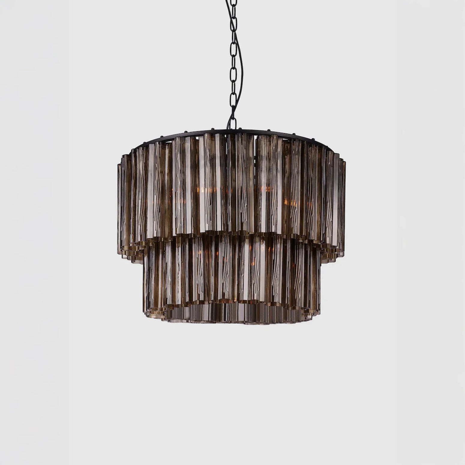 Lysekronen Fontaine Chandelier fra norske Meublé i munnblåst brunt glass med svart oppheng. Her i den mellomste størrelsen, med 2 lag. 