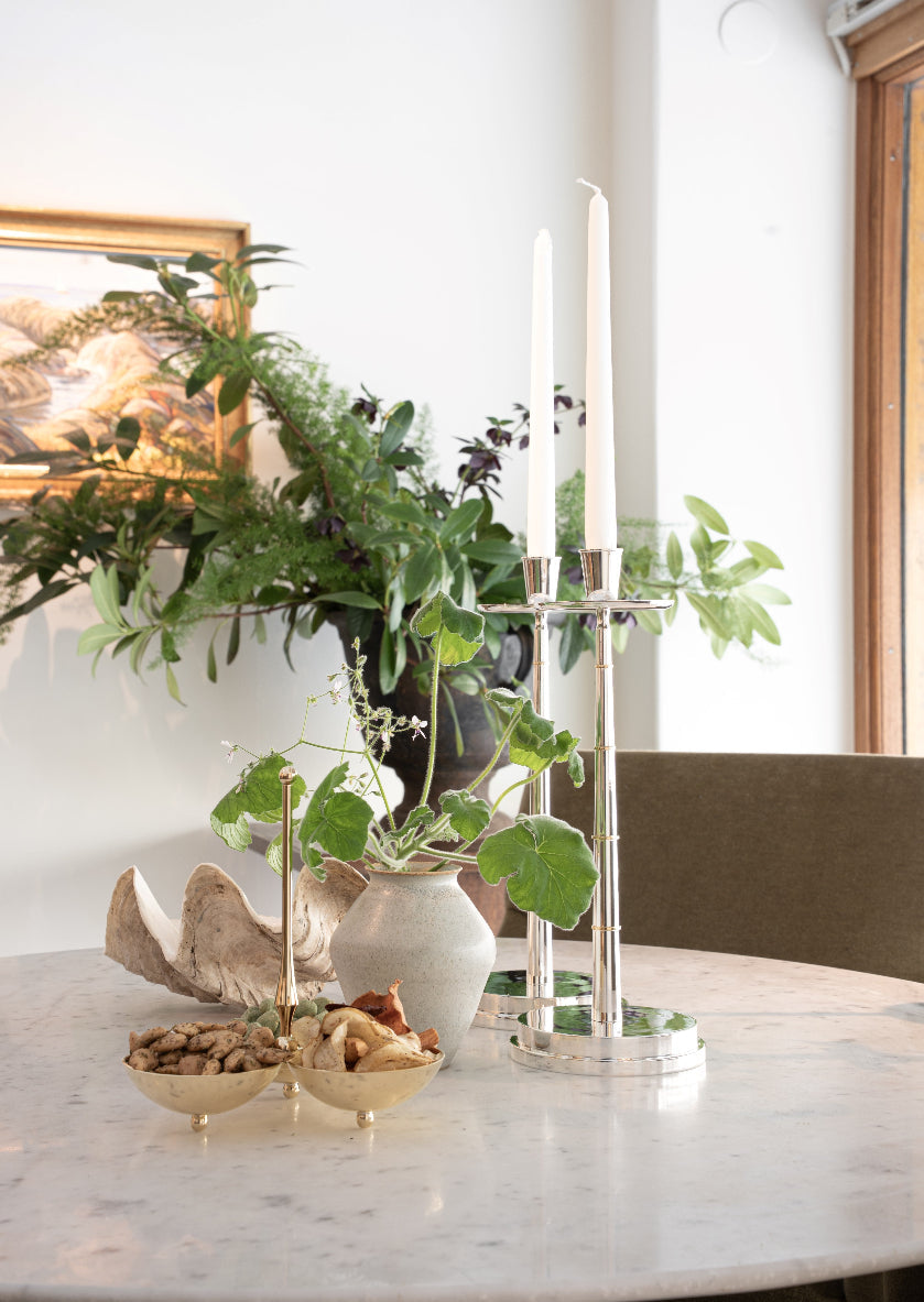 Lysestaken Graceful Candlestick fra Skultuna i sølvbelagt messing stylet plassert på et spisebord i marmor