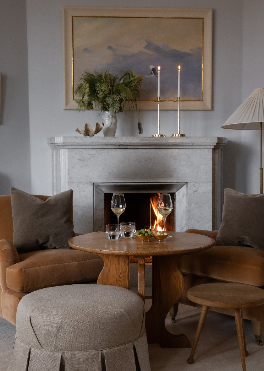 Graceful Candlestick fra Skultuna i forgylt messing brukt som dekorasjon på en peishylle i marmor, med tente lys