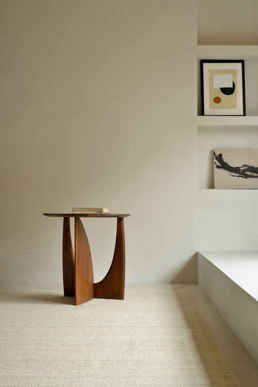 Sidebordet Geometric Side Table fra Ethnicraft er et vakkert og skulpturelt sidebord i heltre med mykt avrundede kanter og et formmessig spennende understell. Buede former og rette vinkler skaper lekne kontraster med lys og skygge og gjør sidebordet til et blikkfang fra alle vinkler.