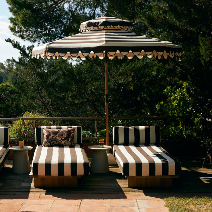 Den mørkebrun- og hvitstripete parasollen Patio Umbrella Stracciatella fra HK Living med bølget kant er som hentet ut av et av Slim Aarons ikoniske fotografier fra 70-tallet – perfekt for deg som ønsker litt ekstra skygge med stil.