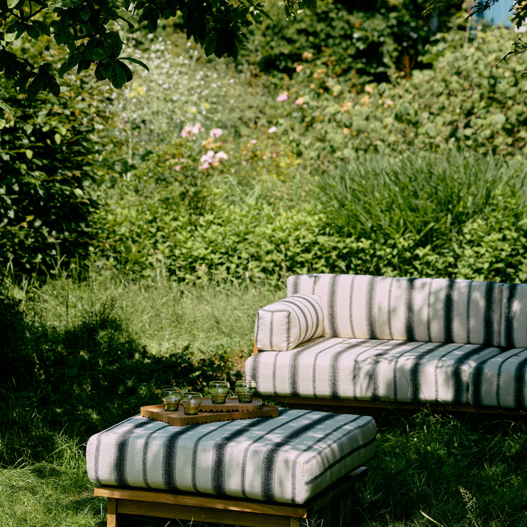 Denne puffen i teak fra HK Living passer perfekt til resten av serien Outdoor Teak, som består av en deilig dagseng og sofa til uteplassen! Puffen Outdoor Hocker Teak kan også gjerne brukes som et bord – og er like mye en ekstra sitteplass som et sted å hvile bena. Rammen er laget i værbestandig teak og du kan velge mellom fire fine tekstiler.