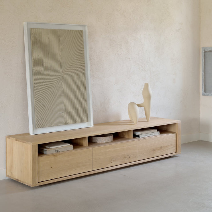 TV-benken Shadow TV Cupboard fra Ethnicraft i heltre eik er renskårent i designet, har raust med oppbevaringsplass og gir rommet en fin tyngde.