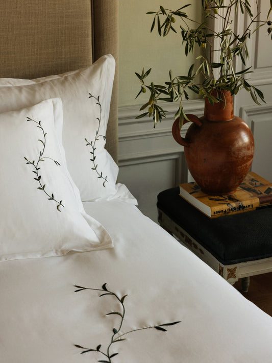 Det krispe hvite sengetøyet Vivace fra Mille Notti med sine slyngende broderte olivengrener i ulike nyanser av grønt gjør soverommet ditt til en liten oase.