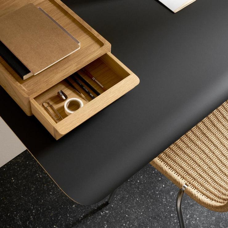 Det vegghengte skrivebordet AB019 Wall desk fra Carl Hansen & Søn kan bestilles med en separat skuff i heltre eik – enten montert under for oppbevaring, eller plassert oppå som et praktisk laptopstativ.