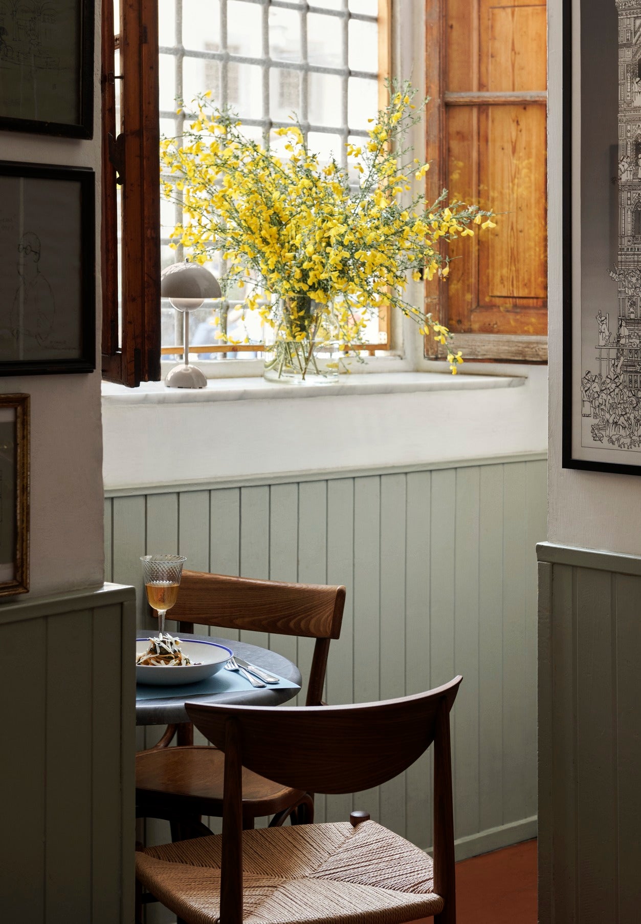 Bilde av en koselig kjøkkenkrok med spisestoler i mørkt tre og grønne vegger. Stolen er Drawn Chair i valnøtt fra &tradition.