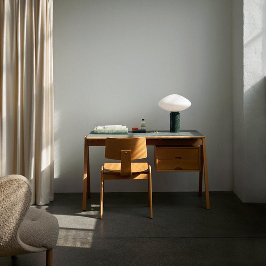 Det nette og vakre skrivebordet Daystak fra &Tradition ble designet av Robin Day – en av de mest betydningsfulle britiske møbeldesignerne innen sjangeren Mid Century Modern – i 1951. Skrivebordet, som er laget i massiv bøk og bøkefiner, har A-formede ben og kan kjøpes med eller uten en avtagbar skuffeseksjon. Her er skrivebordet Daystak RD3 med topplate i grønn laminat. 