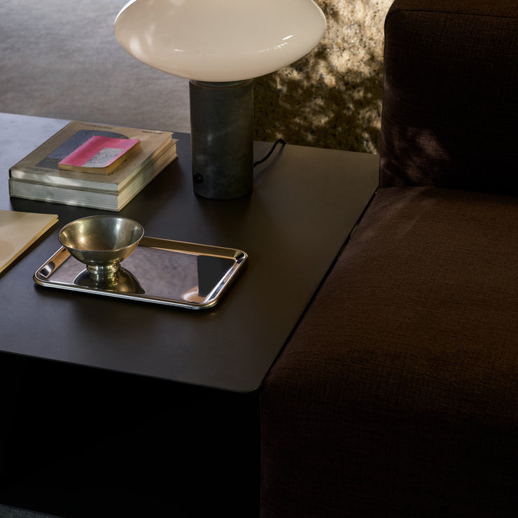 Kvadratisk sofabord Develius EV3fra &tradition, størrelse 89x89 cm i fargen Stone Grey, plassert ved siden av sofamodul i Develius-serien