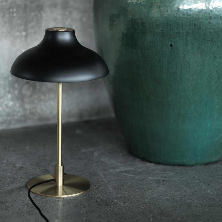 Bordlampen Bolero fra Rubn er inspirert av Mid Century Modern-epoken. Vi liker godt varianten med messingbase og svart skjerm.
