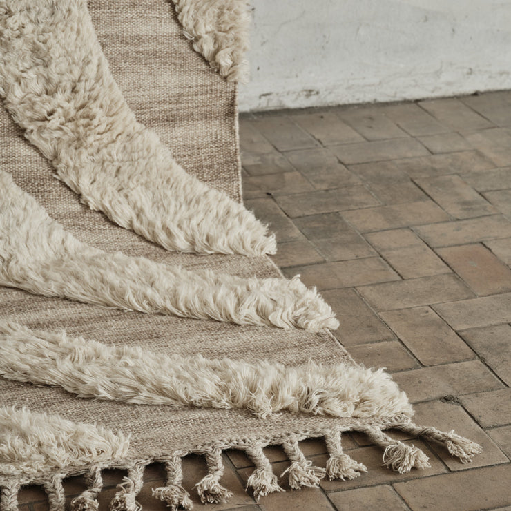 Den flatvevde delen er sandfarget, mens den høyere luven har en myk, off-white farge.