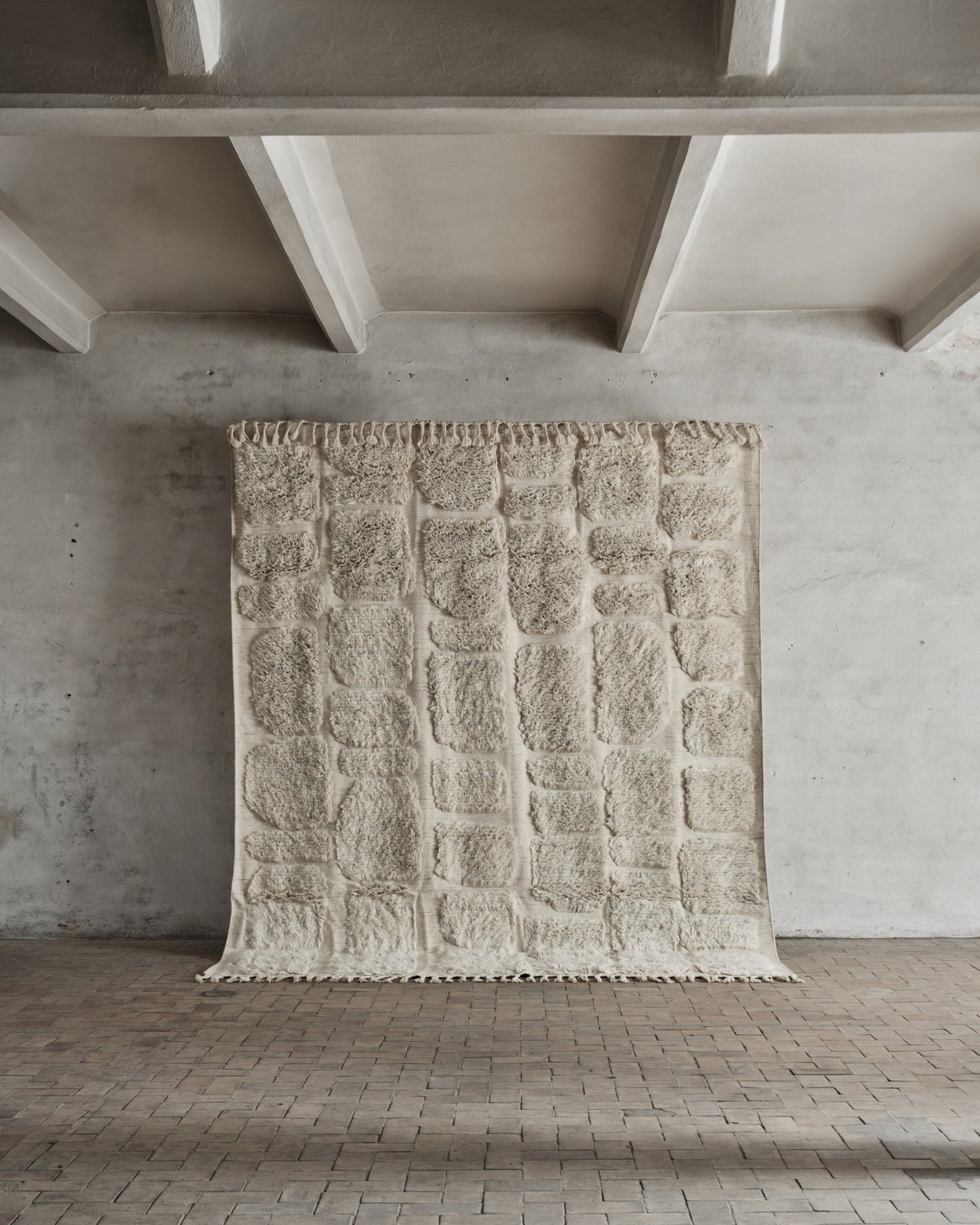 Teppet er håndvevd og laget i naturlig, ubleket New Zealand-ull og bomull og kommer i to størrelser: 230x280 cm og 290x350 cm.