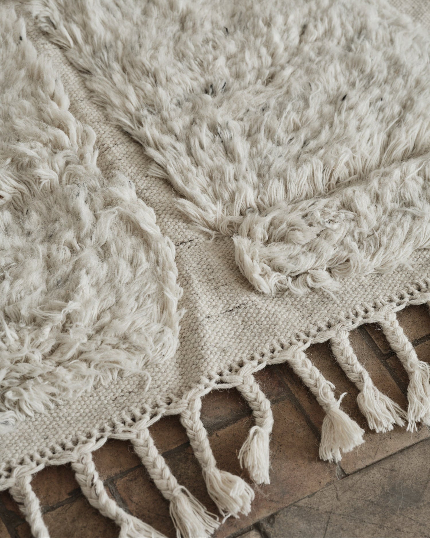 Laget i fargen «shell», en myk, off-white farge, og designet med flettede, tykke frynser på endene er dette et vakkert og lyst – og litt spennende – teppe som vil tilføre ethvert rom et levende uttrykk, enten du har en minimalistisk eller mer maksimalistisk interiørstil.