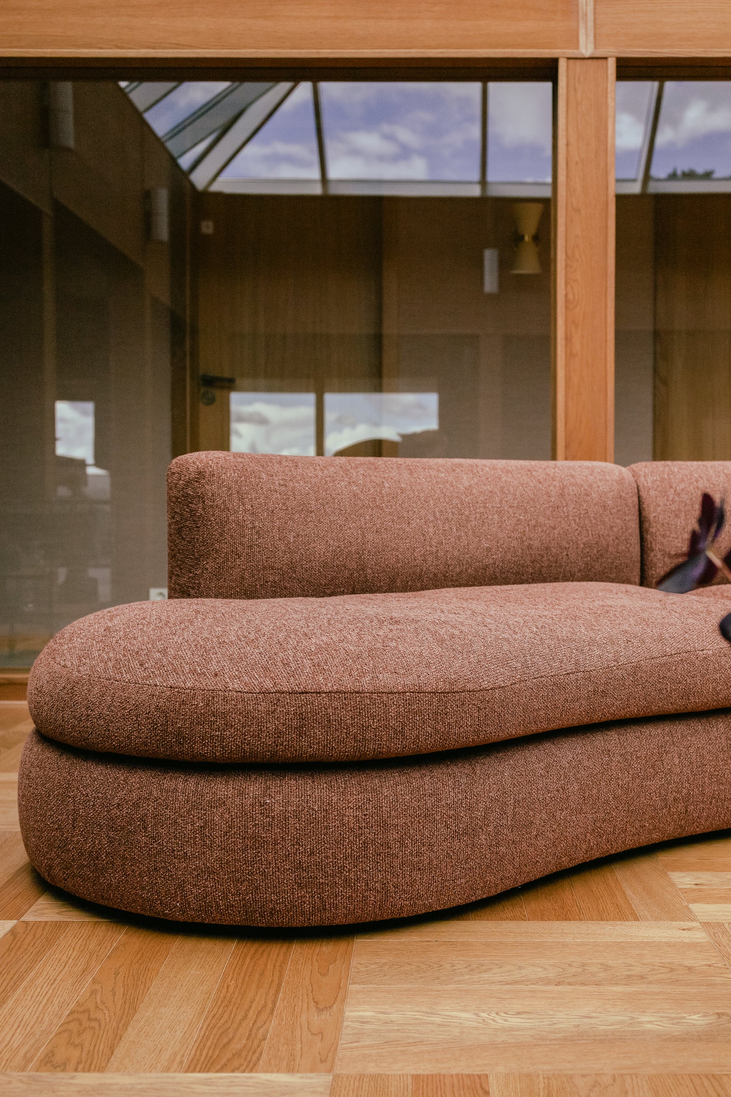 Buet sofa Coda fra New Works i rustfarget bouclétekstil fra OsloDeco i atriumstue renovert av AlexArk. Stuen har varme finerkledde vegger. Foto: OsloDeco