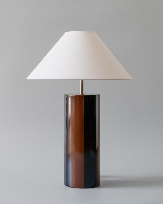Bordlampen Ombrellina Blackberry Syrup & Ginger Bread, i høyblank glasert dyp bjørnebærfarget og brunstripete keramikk med olivengrønn topp, tilhører Renaissance-kolleksjonen, som er inspirert av fargene brukt av malemestere under renessansen samt interiøret fra denne tidsepoken, da mørkt treverk og dype, varme farger regjerte. Formen er likevel moderne – og vi elsker uttrykket!