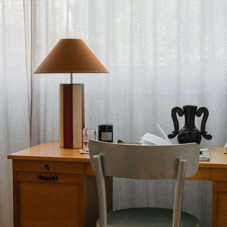 Bordlampen Ombrellina Oxblood & Cognac, i høyblank glasert okseblodrød- og smørkremgulglasert stripete keramikk med blå topp, tilhører Renaissance-kolleksjonen, som er inspirert av fargene brukt av malemestere under renessansen samt interiøret fra denne tidsepoken, da mørkt treverk og dype, varme farger regjerte. Formen er likevel moderne – og vi elsker uttrykket!