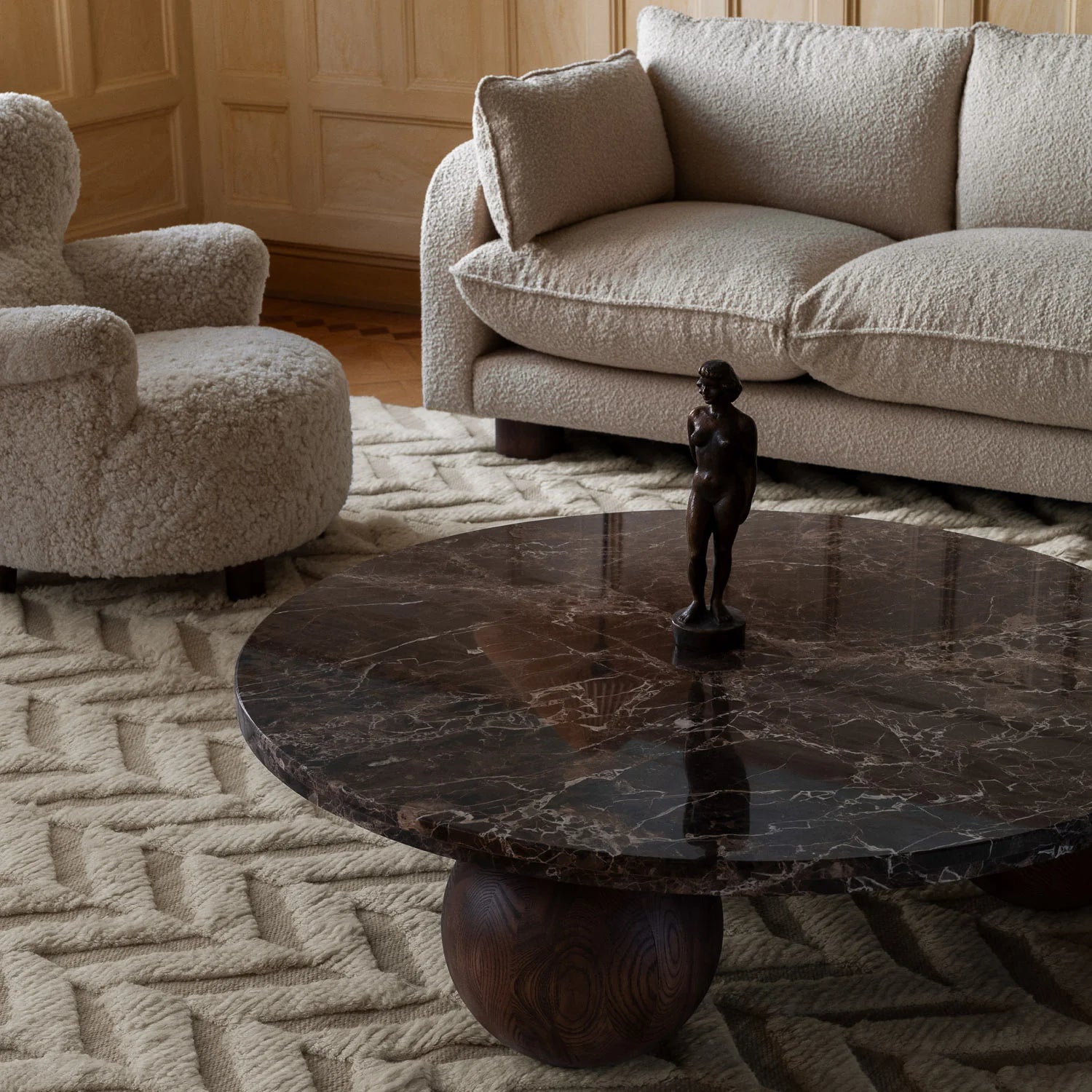 Det runde sofabordet Sphere Round Sofa Table fra Dusty Deco er et formmessig spennende soabord med vakker materialitet. De overdimensjonerte kulene i mørkbeiset bøk støtter en solid bordplate i stein – velg mellom vakker mørkebrun (og blankpolert) Emperador-marmor eller matt lys travertin. 