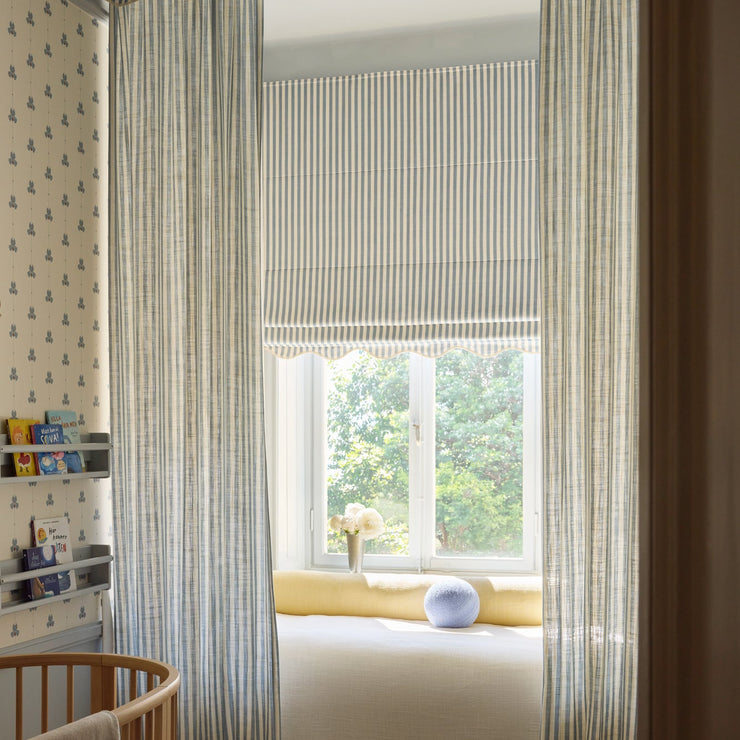 Mørkleggende liftgardin vevd lin Scallop Edge Stripe i fargen dueblå/ Dove Blue fra Gotain. Match med lange gardiner og en gardinkappe for et ekstra spennende og sofistikert uttrykk.