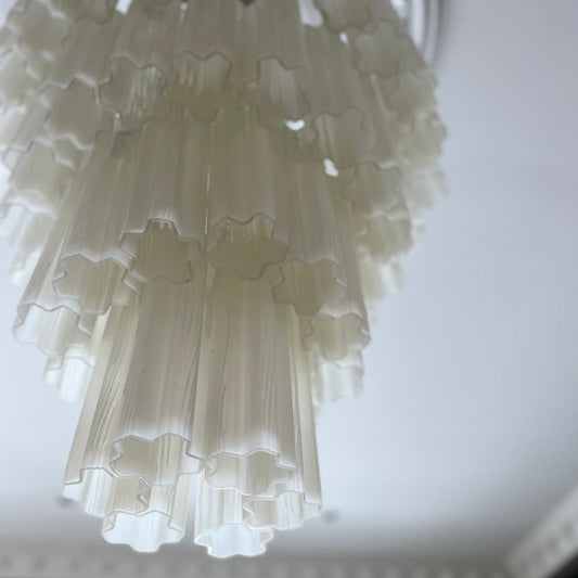 Lysekronen Fontaine Chandelier 4-layer fra norske Meublé smykker ethvert rom den henger i! Vi er spesielt begeistret for den med svart base og melkehvitt glass der de vakkert formede glassylinderne slipper lyset gjennom på en myk og delikat måte.