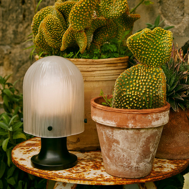 Den oppladbare bordlampen Seine Portable Lamp fra Gubi er en nett og vakker glasslampe som fungerer perfekt som stemningsskaper på balkongen eller i hagen.