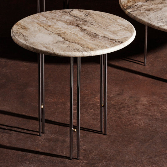 Sidebord IOI Ø50 cm fra Gubi: En rund bordplate i travertin – en nydelig varm kalkstein – hviler på et understell av en samling doble metallrør dekorert med en kule av messing imellom.
