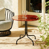 Kafébordet Carmel Bistro Lounge Table i rød/Rock Red og lenestolen Grace Outdoor Lounge Chair fra Gubi i sort/Black.