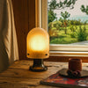 Inspirert av lys som beveger seg over vann, har den oppladbare bordlampen Seine Portable Lamp fra Gubi en rillemønstret, munnblåst glasskjerm som sprer et drømmende, mykt lys.