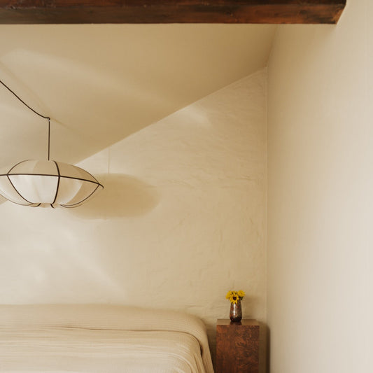 Interiør i loftsleilighet i Oslo, resultat etter interiørhjelp fra OsloDeco. Delikat soverom malt i fargen Soft Touch fra Jotun. Pidestall som nattbord og i taket over sengen henger lampen Indochina i silke. 