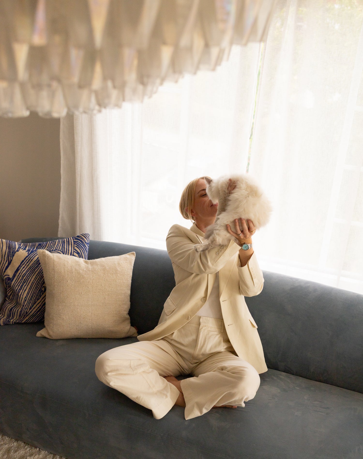 Ida fra Bærum sittende i sin dueblå velursofa kjøpt hos OsloDeco. Puter i blått og krem med spennende tekstur gir liv til interiøret.