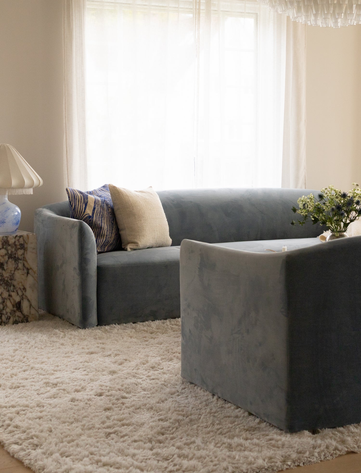 Blå sofaer, to 3-setere, i en klassisk stue med lyse vegger og lett gjennomskinnelige gardiner.  